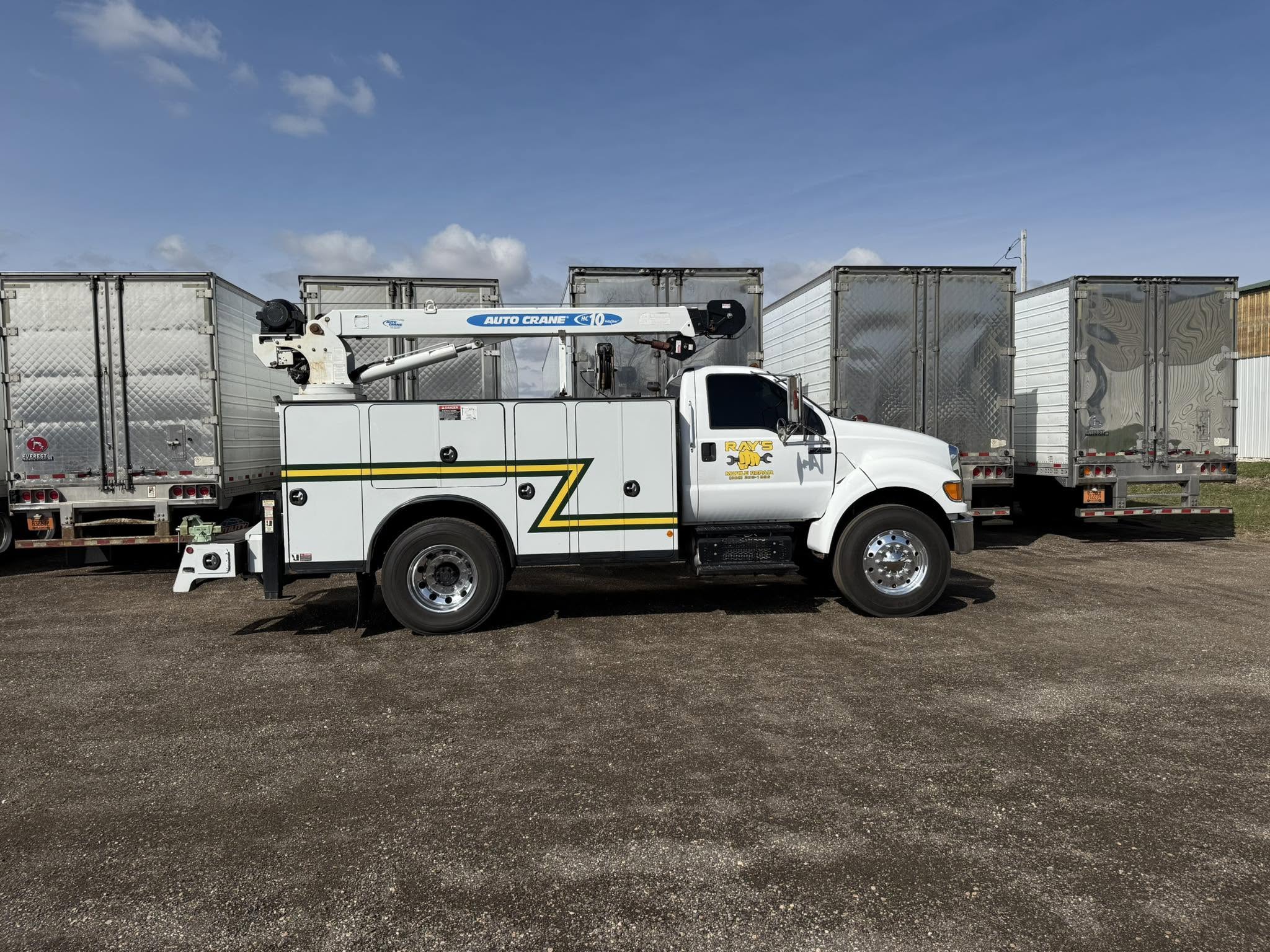 White Ray's Mobile Repair service truck with crane parked by commercial trailers